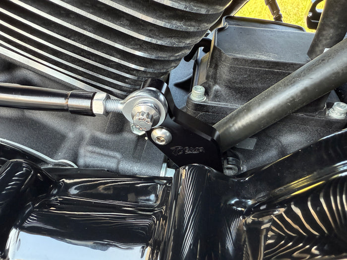 Two metal brackets, one silver and one black, each with a matching screw and bolt, displayed on a white background. Text reads "TC Bros. Pro Series Easy Shift Lever Extension for Harley-Davidson Big Twin—Milwaukee-Eight.