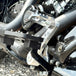The TC Bros. Pro Series Truss Brake Pedal Arm for 2014-Up Harley-Davidson Touring is shown here in disassembled form, including the black metal pedal arm, matching mounting bracket, and a single screw—all displayed against a white background. Perfect for customizing your Touring/Bagger motorcycle or upgrading your Harley-Davidson with this adjustable brake lever setup from TC Bros.