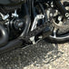 The TC Bros. Pro Series Truss Brake Pedal Arm for 2014-Up Harley-Davidson Touring is shown here in disassembled form, including the black metal pedal arm, matching mounting bracket, and a single screw—all displayed against a white background. Perfect for customizing your Touring/Bagger motorcycle or upgrading your Harley-Davidson with this adjustable brake lever setup from TC Bros.
