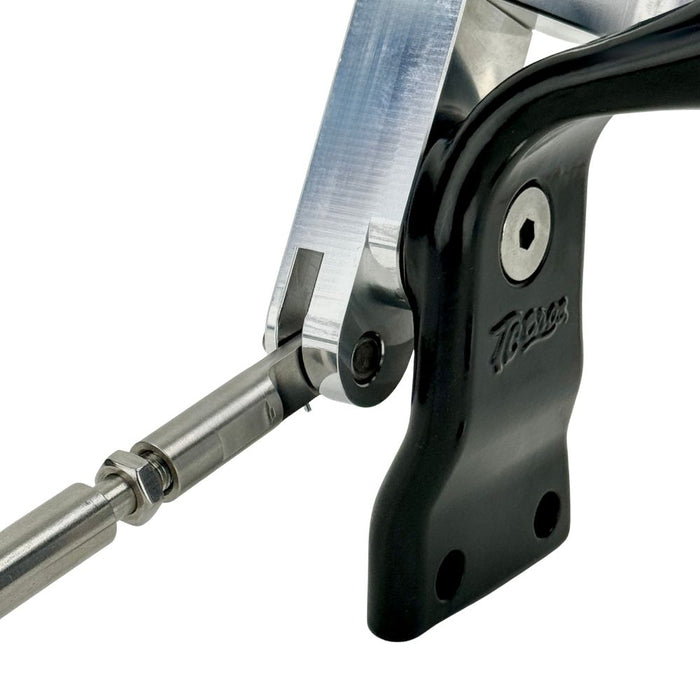 Close-up of a metal hinge mechanism with a black housing, featuring a visible screw and rod connection—ideal for use with the TC Bros. OEM-Style Brake Pedal Conversion Kit for TC Bros. Dyna Mid Controls by TC Bros.