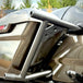 Two black metal TC Bros. Rear Saddlebag Guards with mounting holes, four bolts, two nuts, and four rubber grommets are arranged on a white background—essential components from TC Bros. for installing rear saddlebag guards on 2009-up Harley-Davidson Touring models to enhance rear crash protection.
