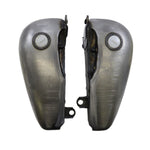 Two metallic flat side gas tanks with visible weld marks, positioned side by side and each topped with a round white cap—these are the Fat Bob-Style Gas Tank - 5 Gallon from Drag Specialties, capturing the classic Harley-Davidson Softail aesthetic while delivering robust performance and enduring style.