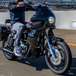 A Saddlemen Mini Fairing in black, specifically for 1996-2005 Dyna Models, featuring a large circular cutout for headlight fitting and a small rectangular side vent designed to enhance wind protection.