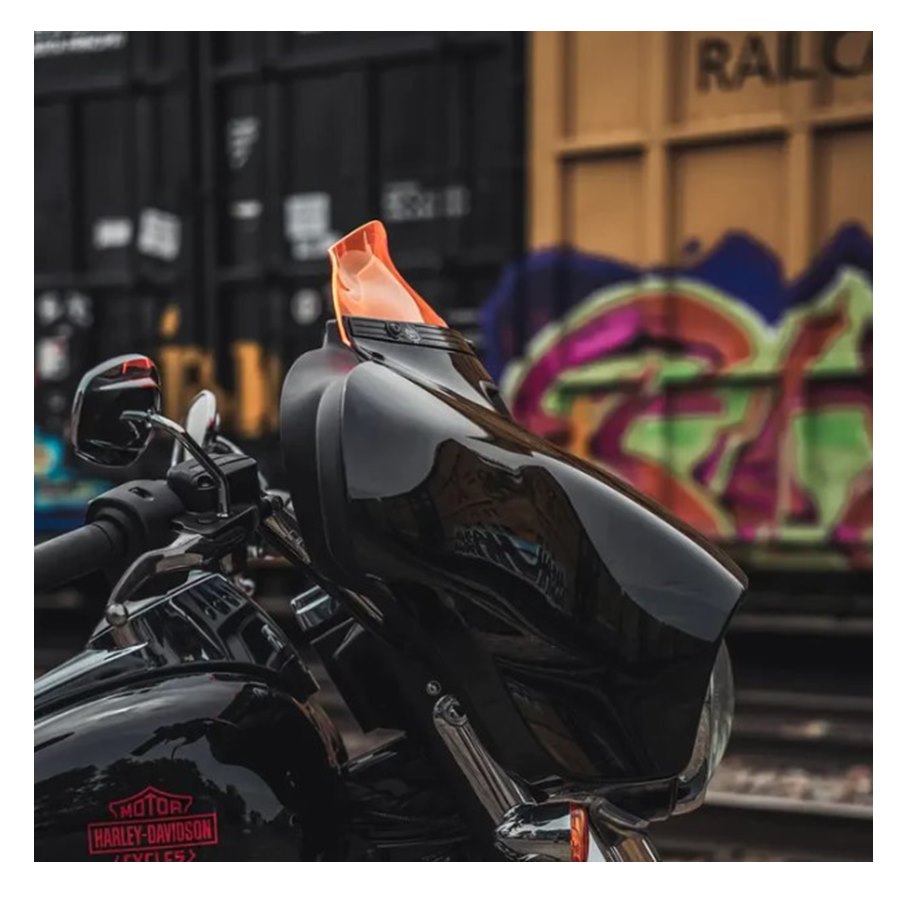 A black Harley-Davidson motorcycle equipped with a Klockwerks Kolor Flare Windshield, parked in front of colorful graffiti-covered shipping containers.