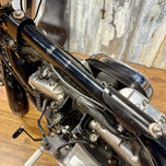 The TC Bros. Frisco Gas Tank Adapter Brackets set for 1982-2003 Harley-Davidson Sportster includes black metal brackets, bolts, washers, nuts, and rubber grommets—perfect for tongue-mount fuel tank installations.