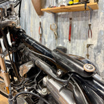 The TC Bros. Frisco Gas Tank Adapter Brackets set for 1982-2003 Harley-Davidson Sportster includes black metal brackets, bolts, washers, nuts, and rubber grommets—perfect for tongue-mount fuel tank installations.
