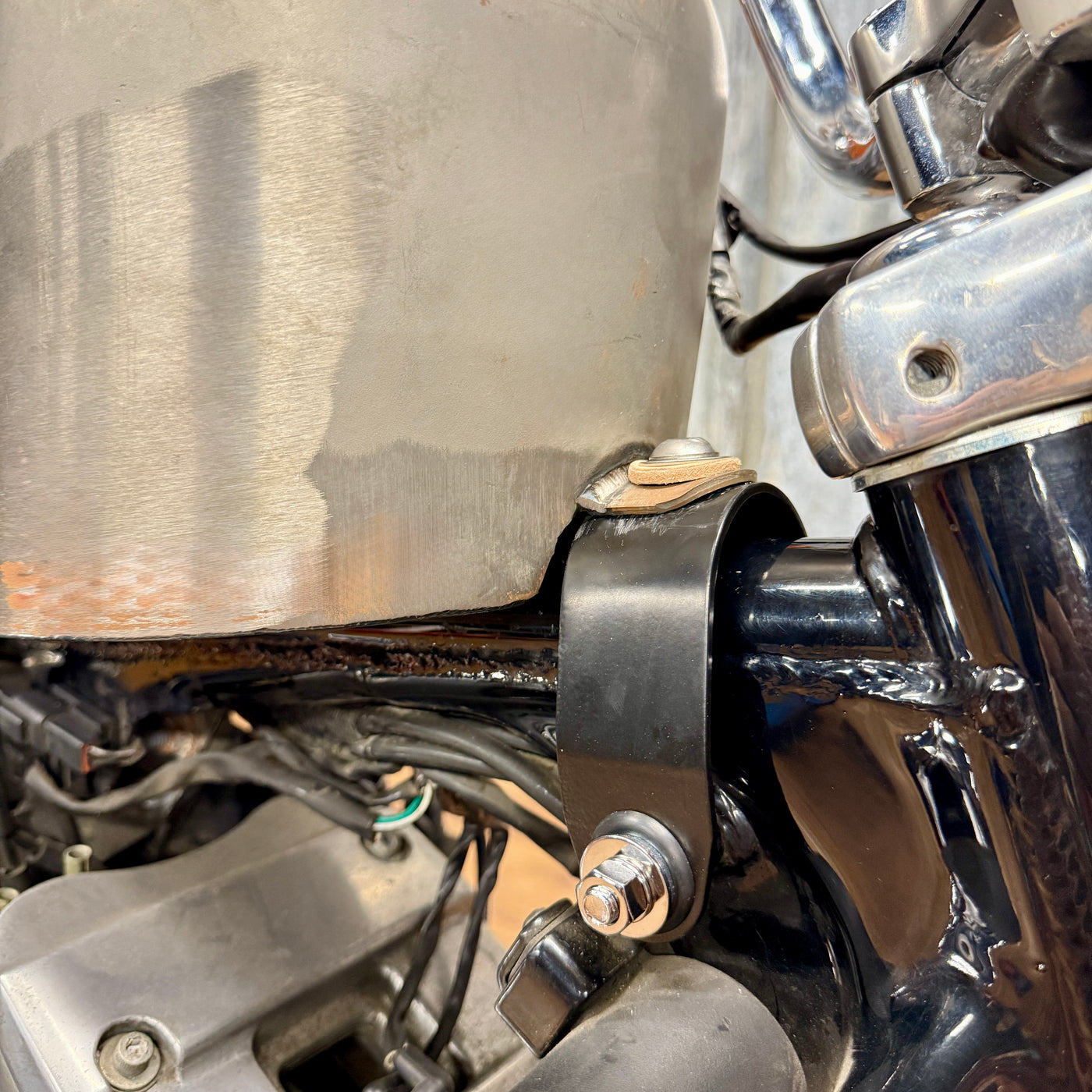 The TC Bros. Frisco Gas Tank Adapter Brackets set for 1982-2003 Harley-Davidson Sportster includes black metal brackets, bolts, washers, nuts, and rubber grommets—perfect for tongue-mount fuel tank installations.