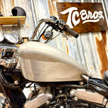 The TC Bros. Frisco Gas Tank Adapter Brackets set for 1982-2003 Harley-Davidson Sportster includes black metal brackets, bolts, washers, nuts, and rubber grommets—perfect for tongue-mount fuel tank installations.