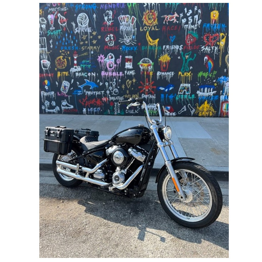 Two black, waterproof Speedwell Vigilante Saddlebags - Harley M8 Softail (with tail light/turn signal kit) with handles, one open and one closed, displayed against a white background.