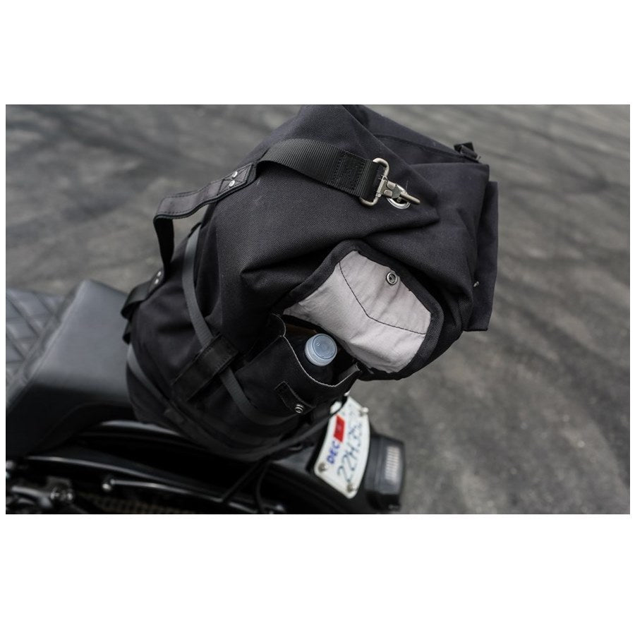 The Burly Voyager Motorcycle Sissy Bar Backpack by Burly is available in black and crafted from durable Black Cordura. It features multiple compartments, a buckled front pocket, and additional side handles. The backpack is also equipped with a MOLLE system for versatile attachment options.