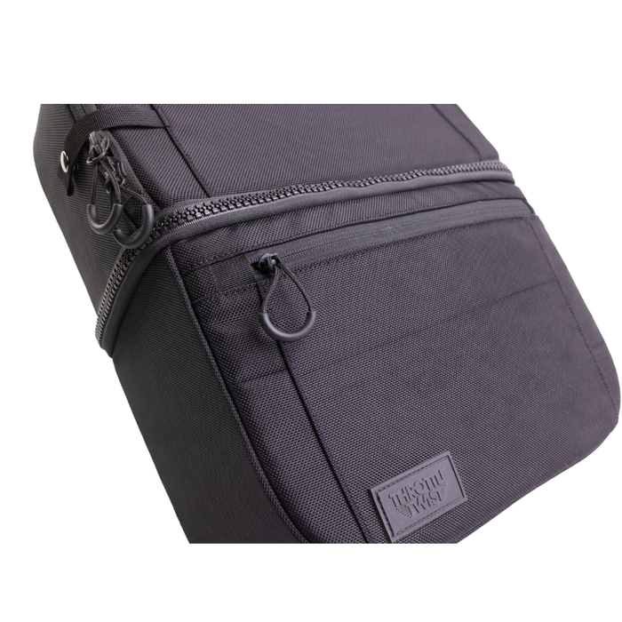 A man stands by his bike with the Throttle Twist Hybrid Saddlebag/Backpack—versatile motorcycle luggage that easily converts into a backpack. Text: "Convertible Saddlebags/Backpack." Brand: Throttle Twist.