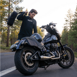 A man stands by his bike with the Throttle Twist Hybrid Saddlebag/Backpack—versatile motorcycle luggage that easily converts into a backpack. Text: "Convertible Saddlebags/Backpack." Brand: Throttle Twist.