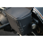 A man stands by his bike with the Throttle Twist Hybrid Saddlebag/Backpack—versatile motorcycle luggage that easily converts into a backpack. Text: "Convertible Saddlebags/Backpack." Brand: Throttle Twist.