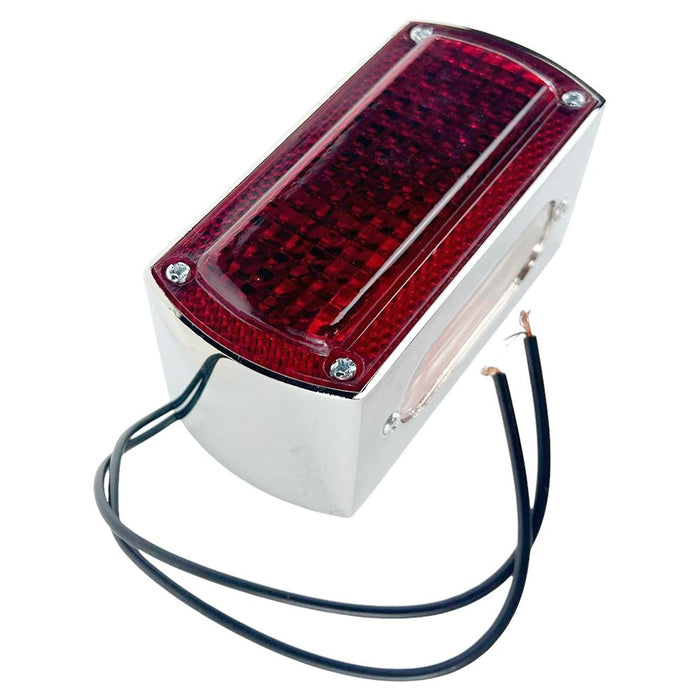 A rectangular red Box Style Chopper Tail Light with a chrome border and exposed black wires for electrical connection, reminiscent of a design by Wyatt Gatling.