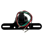 The Mid-USA Vintage Drilled Tail Light by Mid-USA features a round red lens in an aluminum housing, mounted on a black bracket with exposed electrical wires at the back.