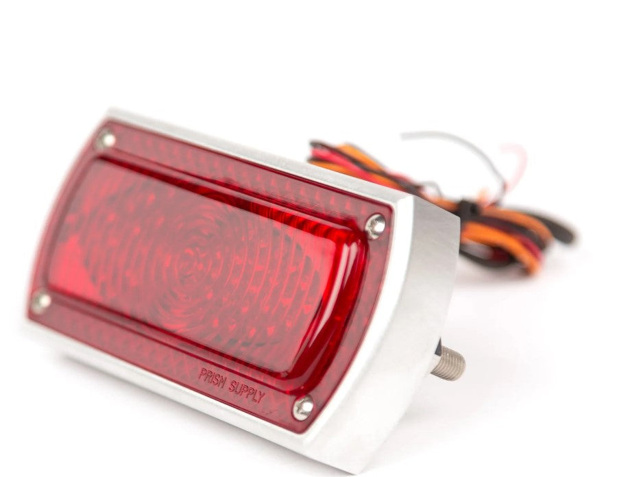 The Prism Supply Box Chopper Tail Light - Brushed is a red, rectangular LED light with a silver frame and multiple wires at the back, offering dual-function capabilities for efficient performance as a brake light.