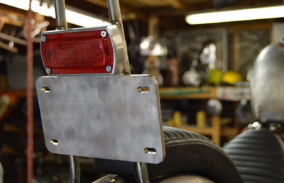 The Prism Supply Box Chopper Tail Light - Brushed is a red, rectangular LED light with a silver frame and multiple wires at the back, offering dual-function capabilities for efficient performance as a brake light.