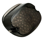 A close-up of the Moto Iron® LED Laydown Squareback Light for 1973-2024 Harley-Davidson, showcasing its dark, rounded design with a smoked lens and integrated turn signals.