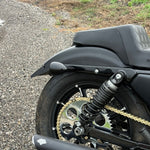 Black metal TC Bros. License Plate Relocation Bracket for 2010-2022 Harley-Davidson Sportster with mounting hardware for saddlebag installation.