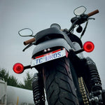 Black metal TC Bros. License Plate Relocation Bracket for 2010-2022 Harley-Davidson Sportster with mounting hardware for saddlebag installation.