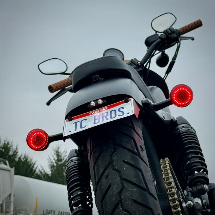 Black metal TC Bros. License Plate Relocation Bracket for 2010-2022 Harley-Davidson Sportster with mounting hardware for saddlebag installation.