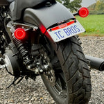 Black metal TC Bros. License Plate Relocation Bracket for 2010-2022 Harley-Davidson Sportster with mounting hardware for saddlebag installation.