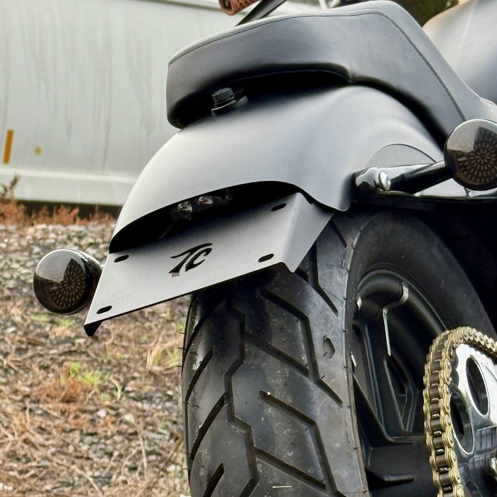 Black metal TC Bros. License Plate Relocation Bracket for 2010-2022 Harley-Davidson Sportster with mounting hardware for saddlebag installation.