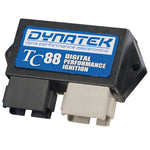 The Dynatek USE NEXT programmable digital ignition module for FXD Big Twin features two electrical connectors—one black and one white.