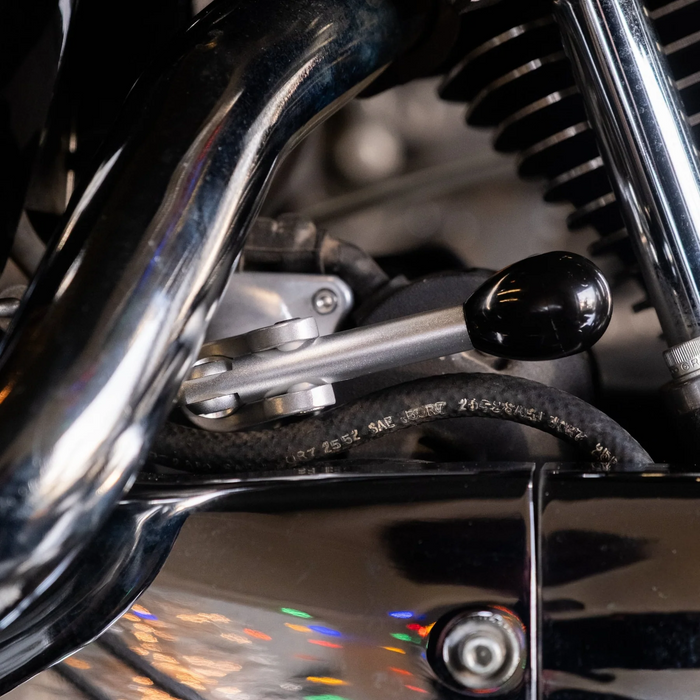 The Prism Supply Quick Stick Start Lever 2.0, a metal solenoid actuator with a black handle and silver base, is designed for Harley-Davidson motorcycles. Shown here against a white background.