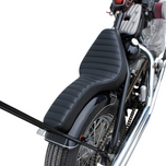 Two black, ribbed TC Bros. Cobra Hardtail Seats are shown, one installed on a motorcycle—ideal for Sportster hardtails or anyone wanting the classic look of a TC Bros. Cobra chopper seat.