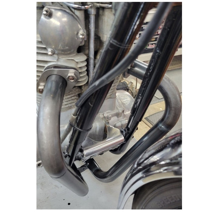 Close-up view of a motorcycle engine and Pandemonium Hustler XS650 exhaust system in a workshop setting.