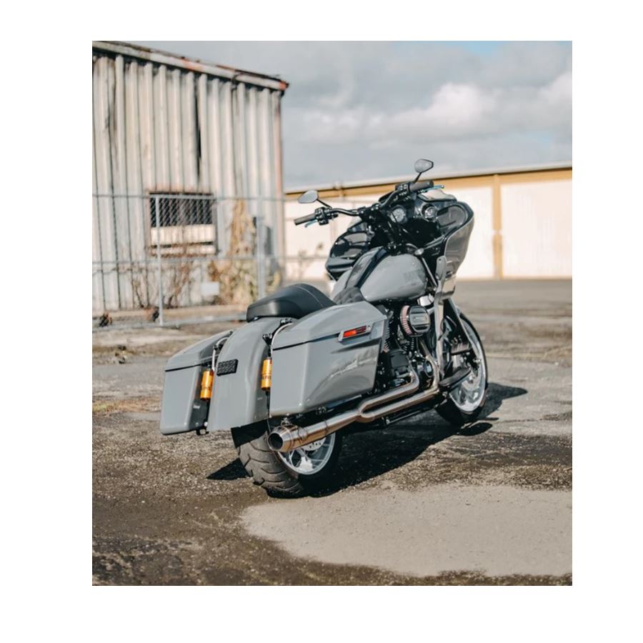 The SP Concepts Full Length Turnpike Works Edition for Harley '17-'24 M8 Touring headers and exhaust pipes made of stainless steel are neatly arranged on the warehouse floor, surrounded by shelves and boxes in the background.