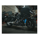 The Fab 28 Stainless Exhaust for 2017-Up Harley-Davidson Touring is shown in front of a wooden American flag with a bull design engraved on the blue field.