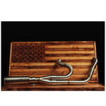 The Fab 28 Stainless Exhaust for 2018-Up Harley-Davidson Softail by Fab 28 is shown in front of a wooden American flag featuring a horse design, ideal for Harley-Davidson Softail enthusiasts.