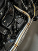 Close-up of a Harley Davidson M8 Softail highlighting the rear wheel, brake disc, and an SP Concepts Mid Length Elsinore Exhaust with a sleek metallic finish and logo.