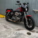 An SP Concepts Lanesplitter Exhaust for Harley Davidson Sportster (1986-2003) is showcased on a textured surface with intricate curves. Nearby, an American flag-patterned helmet hints at the increased torque this meticulously welded stainless steel product promises.