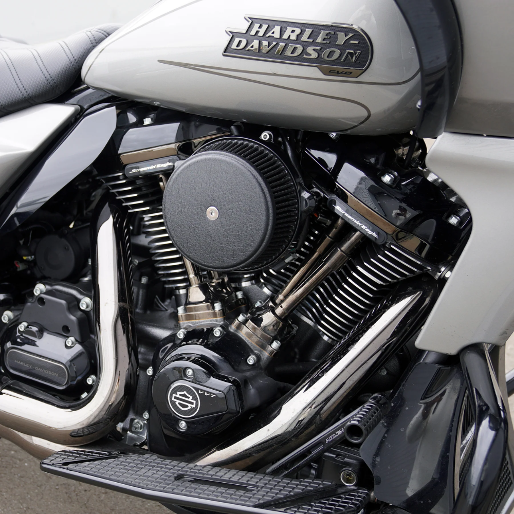 Close-up of a Harley-Davidson motorcycle engine, showcasing Milwaukee-Eight metal components, signature Harley-Davidson branding, the Arlen Ness Big Sucker Stage 1 Air Cleaner for 2023-Up Big Twin models, and part of the bike’s seat and frame.
