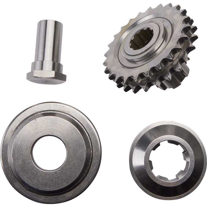 Four metal machine parts—a gear, a cylindrical pin, a circular disc with a central hole, and a round component featuring internal notches—are arranged on a white background. These components are part of the Drag Specialties Compensating Sprocket Kit and are designed for 1984-1990 Harley-Davidson Big Twin Evolution models.