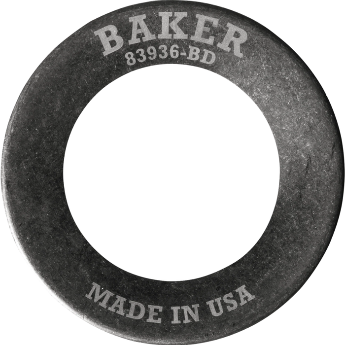 A Baker Drivetrain Comptimizer heavy duty metal washer, engraved with “BAKER” and “MADE IN USA,” is shown angled on a white background—designed specifically for use with 2011-up Harley Davidson Big Twin compensator spring assemblies.