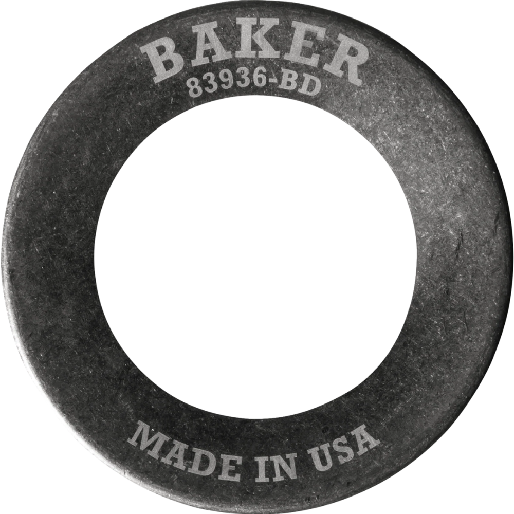 A Baker Drivetrain Comptimizer heavy duty metal washer, engraved with “BAKER” and “MADE IN USA,” is shown angled on a white background—designed specifically for use with 2011-up Harley Davidson Big Twin compensator spring assemblies.