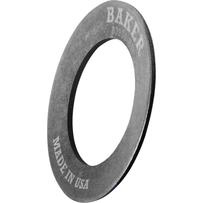 A Baker Drivetrain Comptimizer heavy duty metal washer, engraved with “BAKER” and “MADE IN USA,” is shown angled on a white background—designed specifically for use with 2011-up Harley Davidson Big Twin compensator spring assemblies.