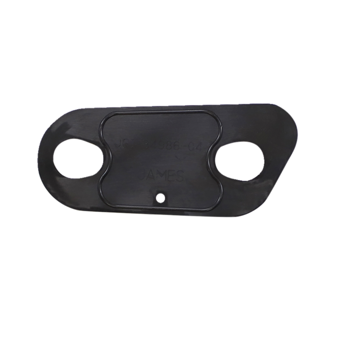 A close-up of a shiny metal engine or machine part, possibly from a Harley-Davidson Sportster, with two smaller metal and rubber gaskets—including a James Inspection Cover Gasket for 2004-2022 Harley-Davidson Sportster by James Gaskets—placed in front of it on a white background.