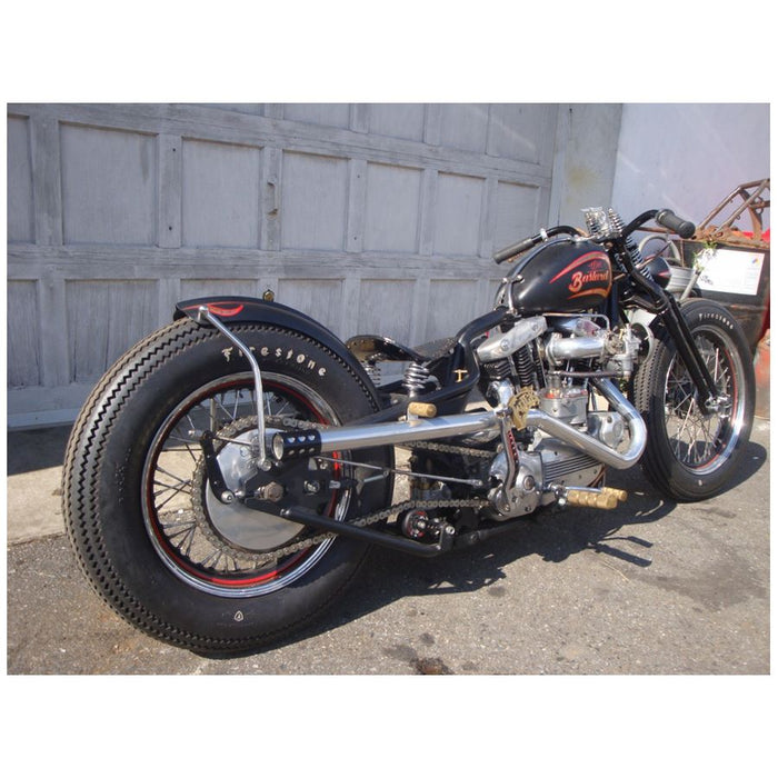 A Monster Craftsman Bolt On Chain Tensioner - Skate Wheel (Powell Peralta) is mounted on a motorcycle parked in front of a garage.