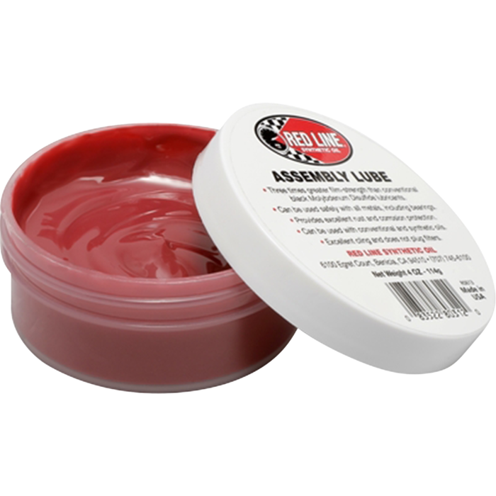 An open container of Redline Oil Red Line Engine Assembly Lubricant with the lid resting at an angle, revealing the pinkish-red lubricant inside.