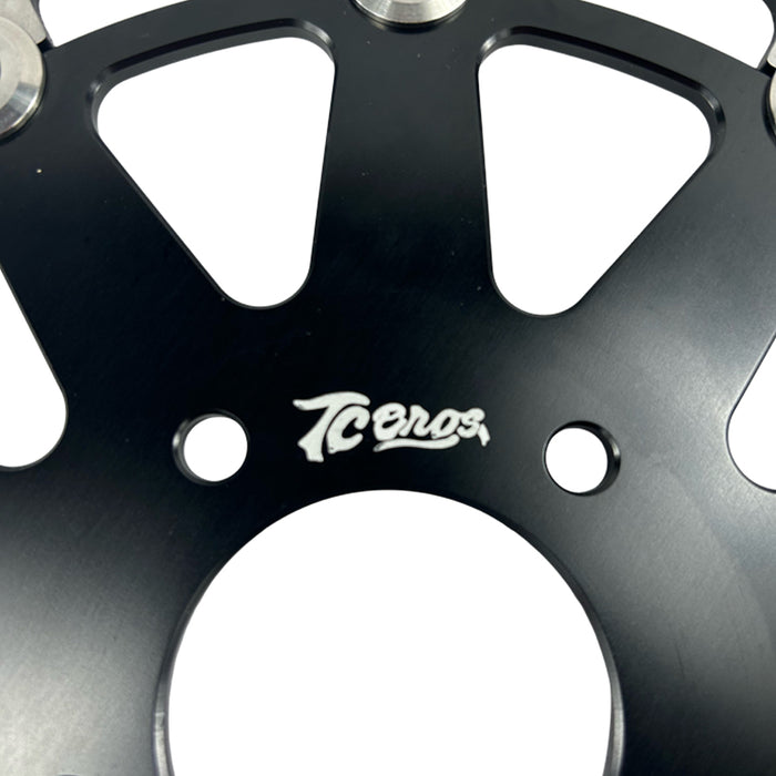 The TC Bros. Profile™ Front Floating Brake Rotor, compatible with 2023+ Harley Touring Bagger and 2021+ Pan America models, features a perforated round design crafted from high-carbon stainless steel with a black center and silver edge.