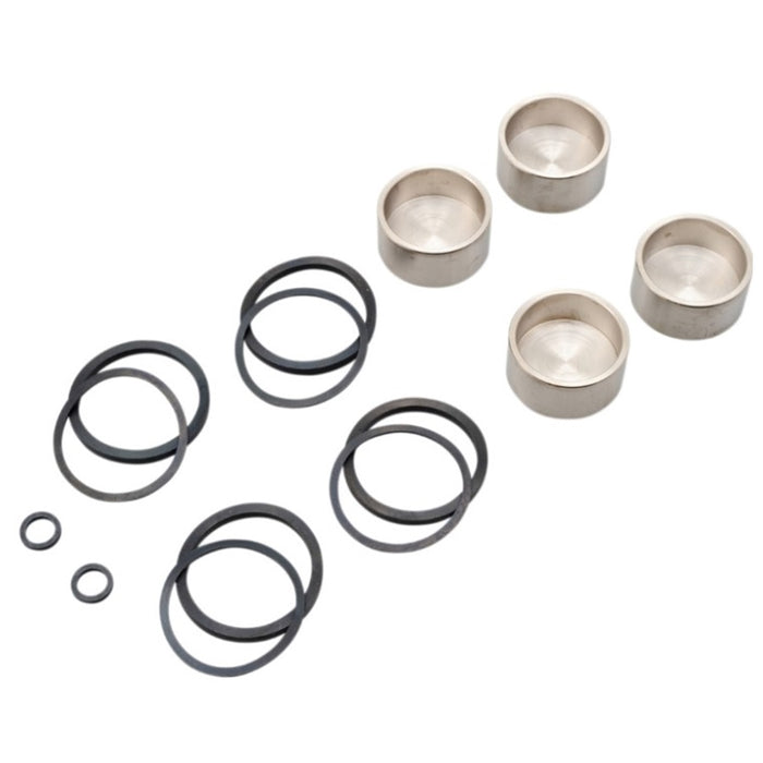 A set of metal cups, black rubber O-rings in various sizes, and two small black neoprene seals arranged on a white background. Ideal for use in a Drag Specialties Front/Rear Caliper Rebuild Kit - For 00-05 Sportster, 00-07 Big Twin, & 00-07 Dyna Models.