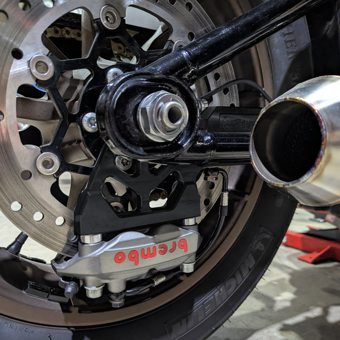 TC Bros. Pro Series Rear Radial Brake Bracket for 2018-Up Harley-Davidson M8 Softail, by TC Bros. Shown in black metal with multiple mounting holes, the kit includes a small attached hose, two bolts, a screw, washers, and copper rings—all arranged below on a white background—ideal for radial caliper conversion.