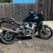 A black motorcycle with TC Bros. Profile™ Rear Brake rotor for 2021-up Harley Pan America Models parked in front of a fence.