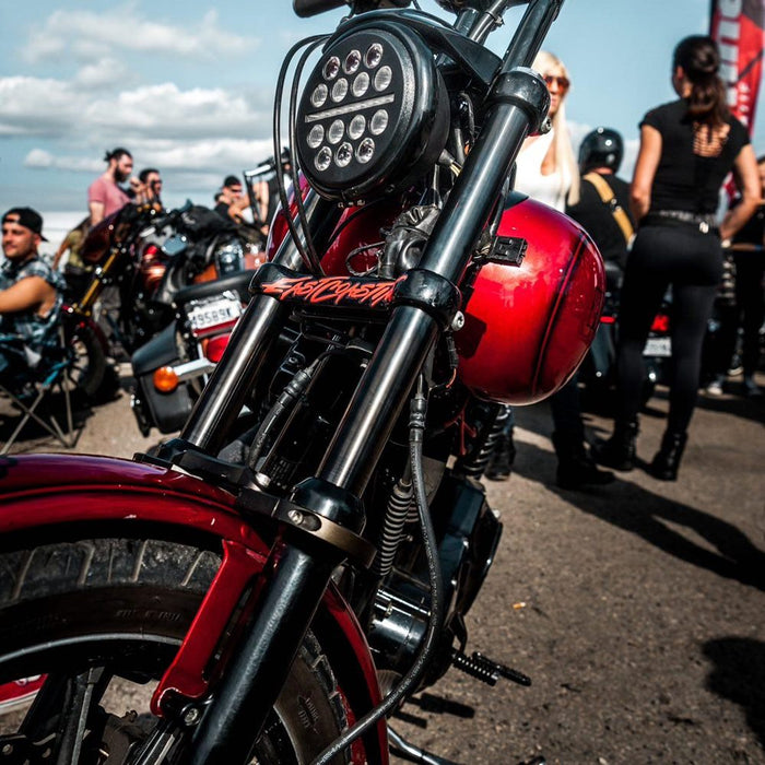 A TC Bros. Black DLC Coated Fork Tubes "Stock Length" 39mm for Sportster/ Dyna Narrow Glide motorcycle is parked in a parking lot. [Fitment Notes]