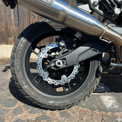 A close up of a motorcycle's front wheel and TC Bros. Profile™ Rear Brake rotor for 2021-up Harley Pan America Models CNC machined brake.